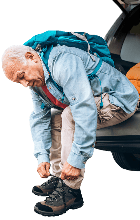 A man wearing a backpack finishes tying his shoes